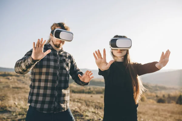 Innovation VR technology concept, two people in virtual reality box glasses gadget technology on road in forest on hills nature background, two people use headset digital for entertainment experience