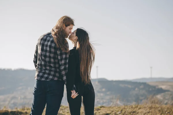 Amore e concetto di San Valentino. Gli amanti adolescenti si accoppiano sullo sfondo naturale della montagna e si tengono per mano guardando al sorgere del sole. Ombra nera amare la gente abbraccio e bacio . — Foto Stock