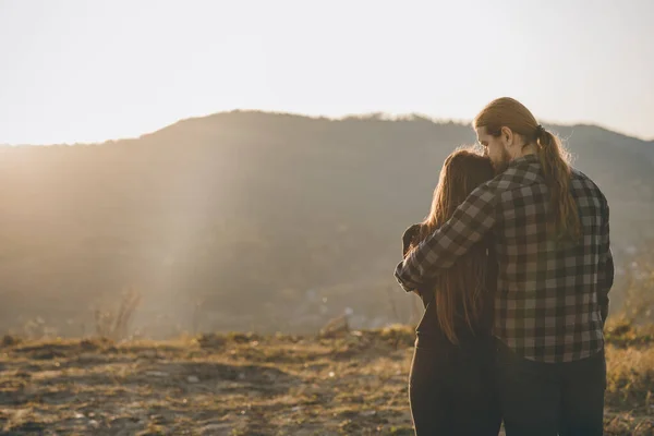 Lovers couple over natural background at the mountain and holding hands looking in the Sun rise. Black shadow loving people hug and kiss. Love and valentines concept.