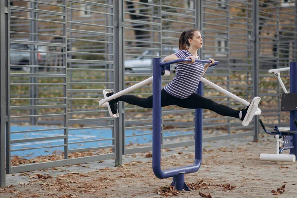 Genç sportif kadın dışarıda spor salonunda yürüyüş egzersizleri yapıyor. Çapraz çalıştırma makinesi kullanıyor. Güneşli bir sabah, kız günlük spor yapıyor. Sağlıklı yaşam tarzı kavramı — Stok fotoğraf