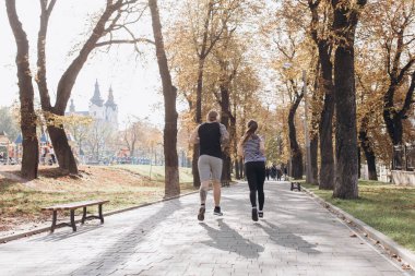 Güneşli parkta birlikte koşan Fitness çifti. Atletik yeni evliler birlikte egzersiz yapıyorlar. Genç adam ve kız spor yapıyor. Spor çifti parkta birlikte koşar. Erkek ve kadın birlikte çalışıyor.