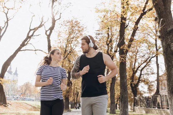 Hombre y mujer en el entrenamiento deportivo juntos. Jóvenes corriendo juntos en el gimnasio al aire libre. Deporte pareja correr juntos en parque . — Foto de Stock