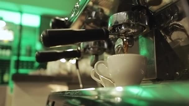 Picie pieczonej czarnej kawy rano. Nalanie strumienia kawy z profesjonalnego urządzenia w dwóch filiżanek. Barista człowiek robi podwójne espresso, za pomocą uchwytu filtra. — Wideo stockowe