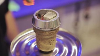 Adam nargile kasesi hazırlıyor ve tüttürmeye hazırlanıyor. Nargile için sıcak közler. Alüminyum folyo üzerine hindistan cevizi kömürü.