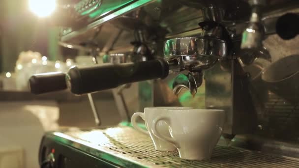 Nalanie strumienia kawy z profesjonalnego urządzenia w dwóch filiżanek. Barista robi podwójne espresso, używając uchwytu filtra. Świeża mielona kawa. Picie pieczonej czarnej kawy rano — Wideo stockowe