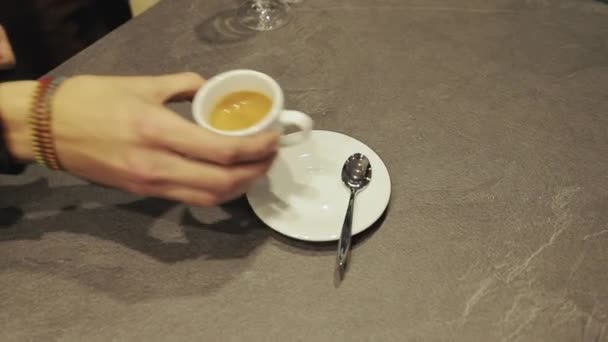 Primo piano di mano mettendo tazza di caffè bianco in ceramica calda con fumo sul piattino sopra il tavolo. Tazza di caffè dato da uomini mani di barman al cliente al caffè . — Video Stock