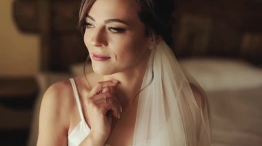 Esmer kız yukarı bakar ve kameraya bakar. Parlak kırmızı dudaklar, güzel bir makyaj..