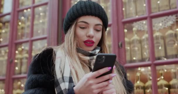 Jovem usando lenço de cabeça andando no centro da cidade, usando smartphone. Comunicação, compras online, conceito de rede social . — Vídeo de Stock