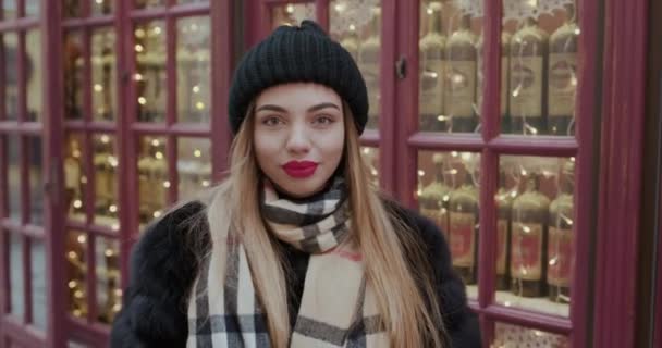 Outdoor Close Up Portrét mladé šťastné usměvavé dívky s červenými rty, na sobě francouzský styl, Pózování v ulici evropského města. Zimní móda, vánoční prázdniny koncept. — Stock video