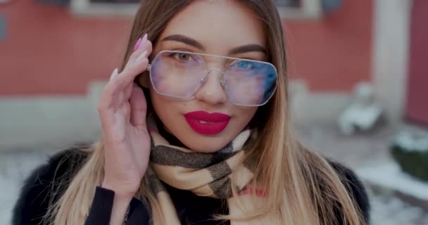 Primo piano del sorriso modello di moda. Donna felice con gli occhiali da sole guardando in macchina fotografica. Giovane donna sorridente su sfondo rosso. Ritratto di ragazza felice sorridente in città . — Video Stock