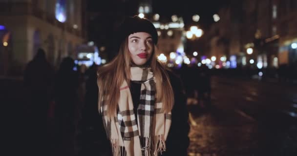 Close-up gezicht van een mooie glimlachende vrolijke vrouw kijkt naar de camera. Mooi jong meisje poseren 's nachts op straat. — Stockvideo