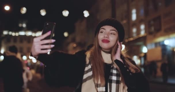 Menina caucasiana feliz fazendo selfie. Menina modelo elegantemente vestida posando nas ruas da cidade . — Vídeo de Stock