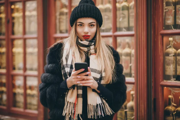 Krásná mladá žena se smartphonem, co posílá zprávy. Dospělá kavkazská žena používá aplikaci Smartphone mimo moderní budovy — Stock fotografie