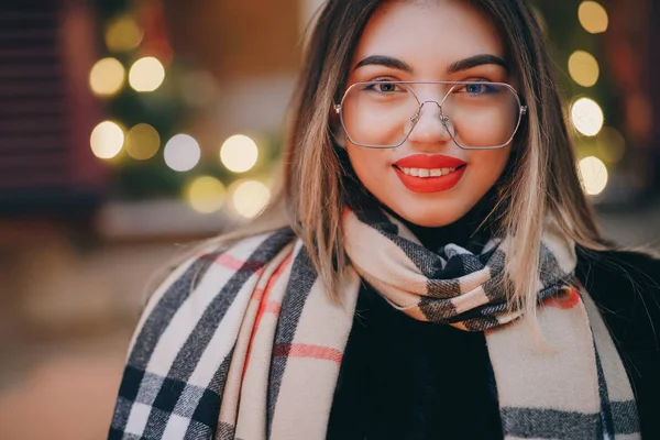 Kobieta w okularach patrzeć na aparat pozuje w centrum miasta Piękne włosy atrakcyjny uśmiech dziewczyny. Zamknij strzał Kobieta w okularach w czasie zimy. Koncepcja technologii, zimy i wakacji. — Zdjęcie stockowe