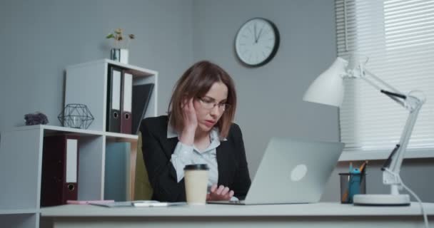 Mujer cansada con gafas sentada en la computadora portátil mientras trabaja en la oficina, luego casi se duerme y se despierta — Vídeo de stock