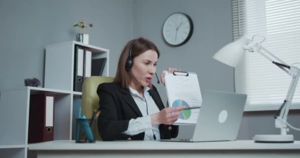 Businesswoman Holding Paper Οικονομική Έκθεση Ομιλία στο Webcam κάνει Video Call στο Γραφείο, Business Coach Κοιτάζοντας Κάμερα Speak Εμφάνιση Στατιστικά Εξηγήστε τη στρατηγική μάρκετινγκ για τον πελάτη — Αρχείο Βίντεο