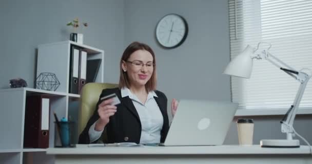 Retrato de la hermosa empresaria bailando sentada en su escritorio. Mujer exitosa y feliz celebrando ventas récord. Mujer joven creativa baila mientras se sienta en su escritorio del lugar de trabajo . — Vídeo de stock