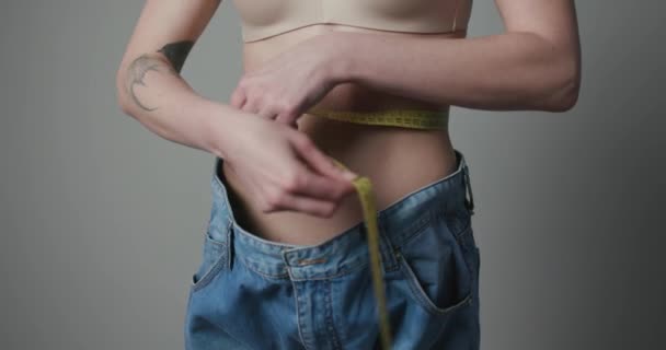 Жінка контролює свої заходи за допомогою стрічки. Жінка вимірює своє тіло. Концепції втрати ваги . — стокове відео