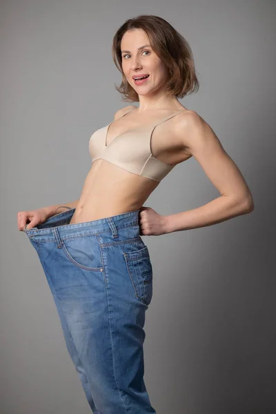 Женщина, восхищающаяся результатом потери веса во время ношения старых джинсов. Счастливая женщина после потери веса . — стоковое фото