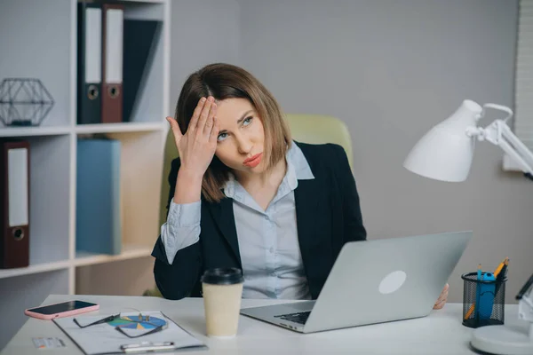 Tired woman in glasses sitting at the laptop computer while working in the office, then almost falling asleep and waking up. Indoor — Stock Photo, Image