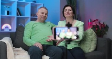 Vlog yazarı çevrimiçi izleyicilerden kanalını sevmelerini ve abone olmalarını istiyor. Mutlu gülümseyen son sınıf çifti ve torununun evde video kaydı var..