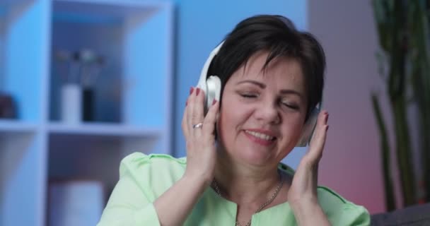 Happy Woman Listening Music on Headphones and Dancing in Home Having Fun (em inglês). Conceito de Tecnologia, Pessoas e Estilo de Vida - Happy Senior Woman in Headphones Listening to Music at Home — Vídeo de Stock