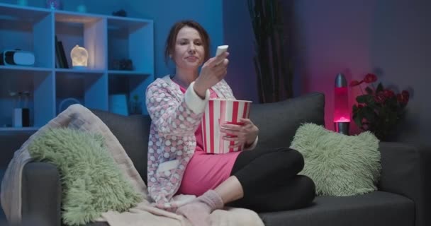 Посміхаючись, сміється жінка дивиться комедійний фільм вдома — стокове відео