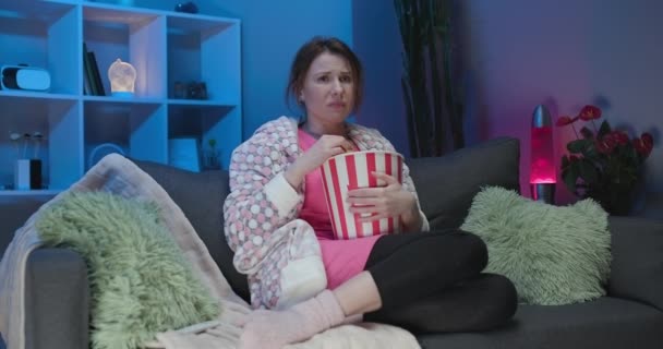 Ung kvinna gråta medan du tittar på en mycket rörande film med popcorn på natten — Stockvideo