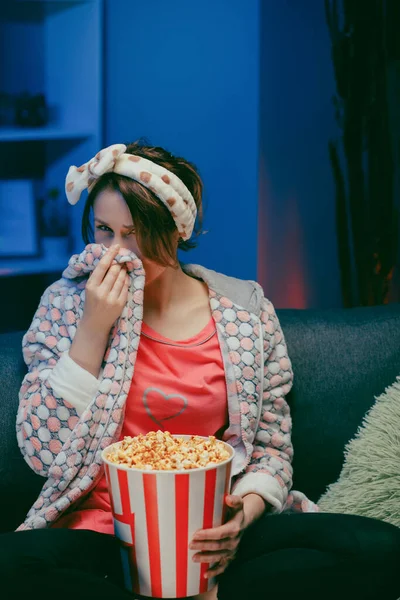Junge Frau weint, während sie sich nachts einen sehr bewegenden Film mit Popcorn ansieht — Stockfoto