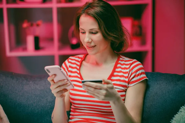 Woman are buying online with a credit card and smile while sitting on the sofa at home. Woman are using smart phone and doing online transactions, Past the internet — Stock Photo, Image