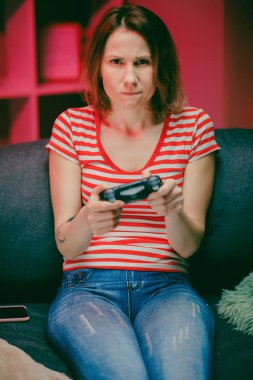 Geceleri oturma odasında video oyunu oynayan bir kız. Kanepede oturan, video oyunlarında konsolda oynayan ve kablosuz kumanda kullanan bir kadın..