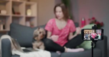 Konuşan genç bir kadın sohbet ederken gülüyor ve internette akıllı telefona bakarak sohbet ediyor. Neşeli kız blog yazarı etkileyicisi kanal için kamera kayıt vlog 'una konuşuyor