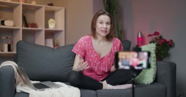 Neşeli genç kadın blogcu kamera kayıt vlog 'una konuşuyor. Mutlu genç kız video konuşuyor, uzaktan arkadaş arıyor, akıllı telefona bakıyor..