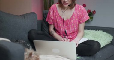 Mutlu kadın konferans görüşmesiyle iletişim kuran kulaklık takıyor evdeki bilgisayara bakıyor. Çevrimiçi öğretmen kavramına sahip video sohbet iş görüşmesi veya uzaklık dili kursu