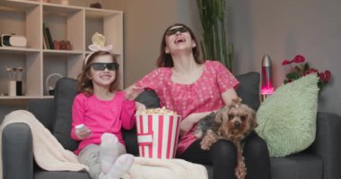 Aile birlikte 3D film izliyor, 3D gözlükler takıyor ve patlamış mısır yiyor..