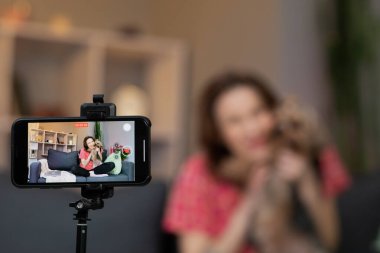 Kadın blogger vlogger etkileyicisi evde oturup kameraya bakarak konuşuyor ve video konferans kaydı yapıyor. Ev konseptinde video sohbeti yapan yaşam tarzı blog günlüğü