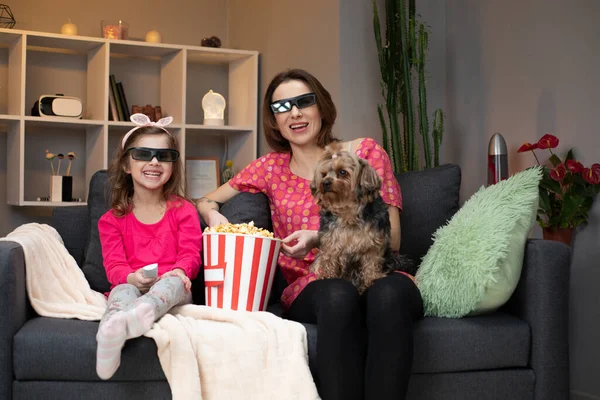 Joyful Kaukasische vrouw en haar dochtertje in 3D bril zitten op de bank en kijken naar comedy film op TV terwijl het eten van popcorn en lachen. — Stockfoto