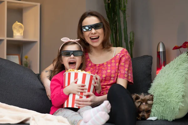 Familie tijd ontspannen met jong meisje kind op de bank in woonkamer concept. vrouw met een klein meisje dragen 3D bril kijken tv en eten popcorn. — Stockfoto