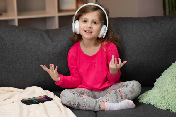 Zabawna dziewczynka w bezprzewodowych słuchawkach tańcząca śpiewająco i poruszająca się w rytm. Dziewczynka w słuchawkach. Dzieciak w słuchawkach. Szczęśliwa dziewczynka słuchająca muzyki ze słuchawkami — Zdjęcie stockowe