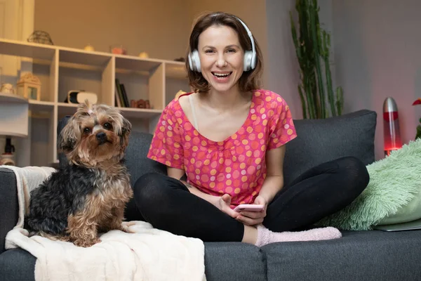 Vrouw en haar hond met hoofdtelefoon luistert naar een muziek — Stockfoto