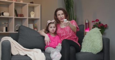 Kadın kızı TV'ye bakıyor ve gülüyor.