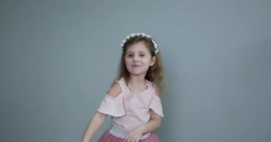 Lale buketli küçük kız. Gri arka planda elinde sarı bir lale tutan bir kız.