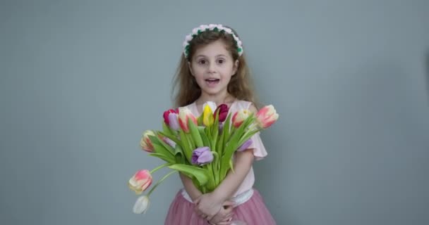 Bambina con tulipani primaverili bouquet di fiori. Bella bambina con un mazzo di tulipani. Ragazzina che mostra un mazzo di fiori assortiti. Ragazza sorridente con mazzo di fiori . — Video Stock
