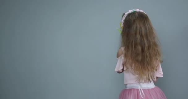 Meisje met een boeket lentebloemen op achtergrond. Een kind met een tulp in zijn hand. Ruimte voor tekst. Voorjaarsconcept — Stockvideo
