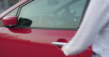 Kadın eli, kırmızı arabanın kapısını açar. Genç güzel kız kapıyı aç ve arabada otur. Sürmeye hazırız. Ulaşım konsepti. Kız kırmızı bir arabada oturuyor, kapıyı açıyor..