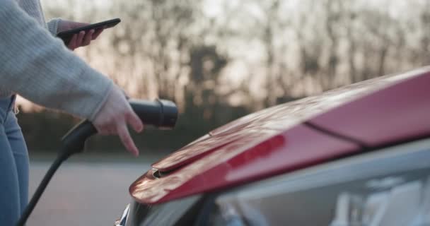 Elektromos jármű csatlakoztatása akkumulátortöltéshez a parkolóban. Közelről. Csatlakoztatott töltő kábel elektromos jármű, EV parkoló, elektromos töltő kábel, töltőállomás, fenntartható jövő — Stock videók