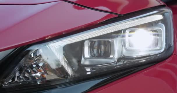 Car with headlight flashing smoothly close up. Car led light with a blurry background and a nice colour. — Stock Video