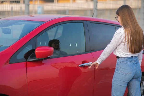 Attraktiv kvinna som använder modern teknik för att låsa upp bildörrar. Kvinnan öppnar dörren och sätter sig i bilen. En tjej öppnar bilen och sitter inne. — Stockfoto