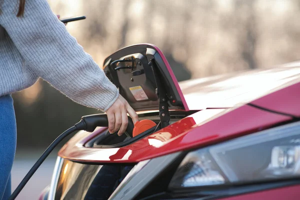 Woman is plugging electric vehicle for charging car battery at parking. Close up. Plugged charging cable electric vehicle, EV parking, power charger cable, charging port station, sustainable future. — Stock Photo, Image