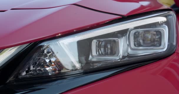 Auto met koplamp Flitsen soepel close-up. Car Front Led Light met een wazige achtergrond en een mooie kleur. Auto koplampen Knipperende LED-lamp — Stockvideo